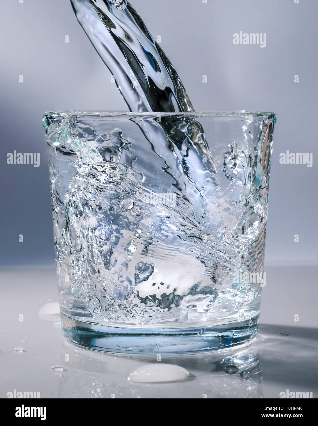 Un bicchiere di vetro in cui acqua fresca è versata Foto Stock