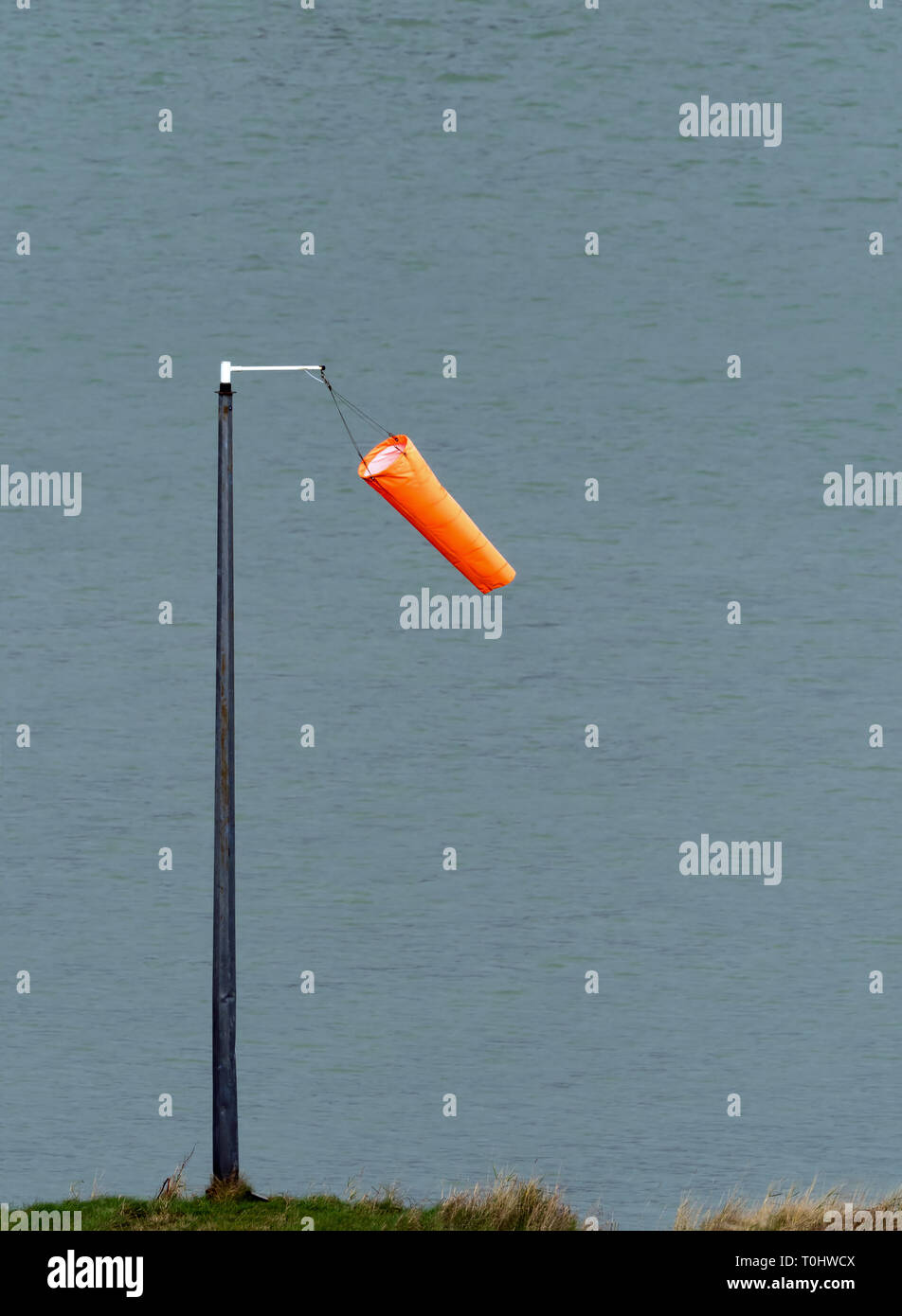 Vento arancione calza appesa limply in condizioni di vento leggero da Sussex Harbour. Foto Stock