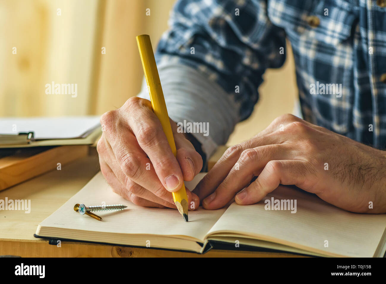 Carpenter la scrittura di note del progetto in small business workshop di falegnameria Foto Stock
