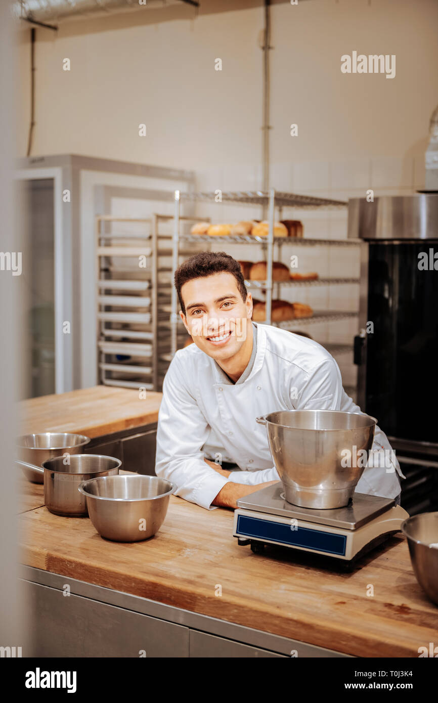 Professional baker sorridente avente il suo primo giorno nel nuovo forno Foto Stock
