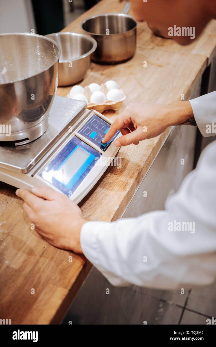 Baker mediante bilancia da cucina durante la pesatura mantecato bianchi Foto Stock