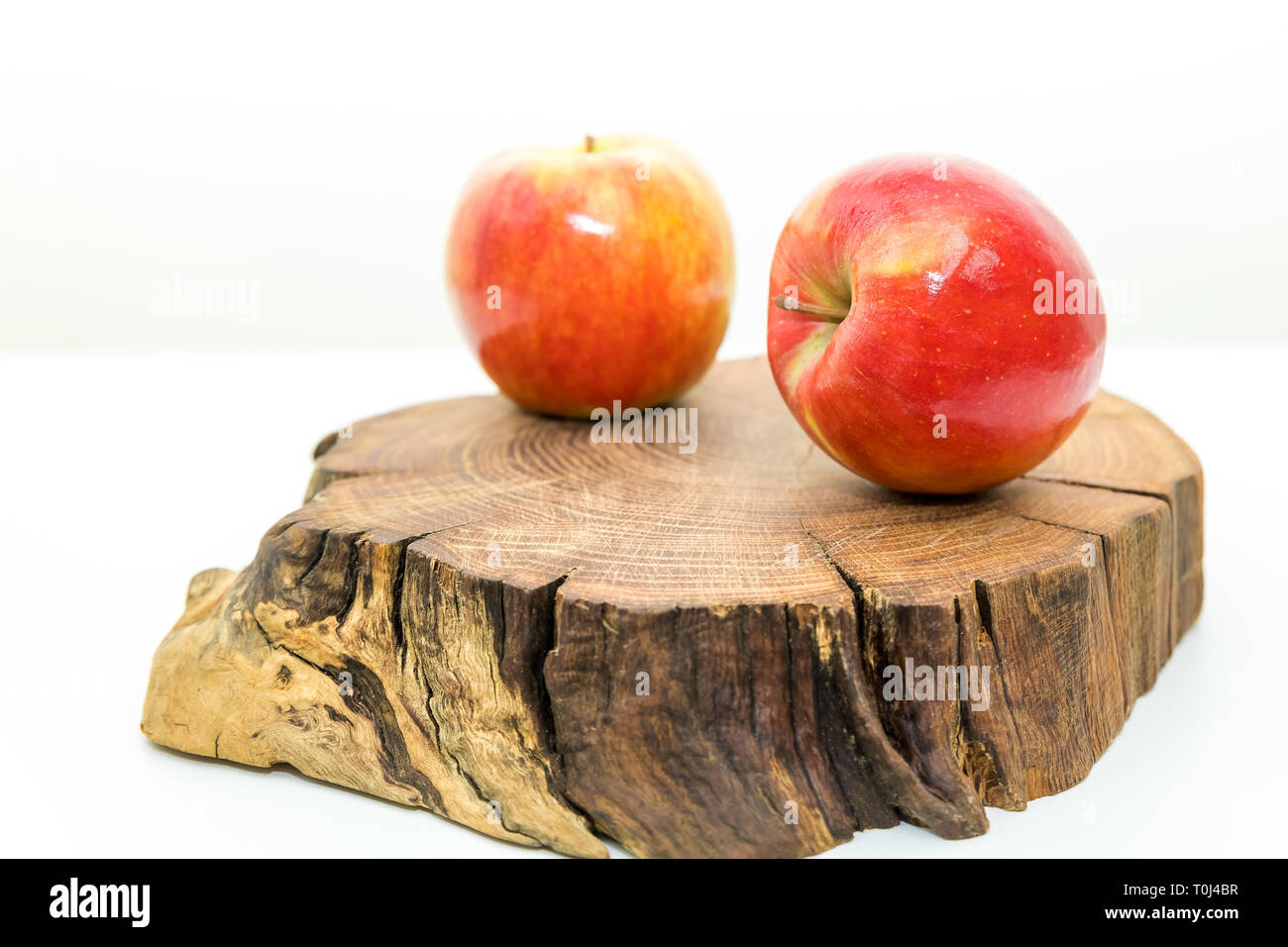 Due rossi Mele succose giacciono su un ceppo di legno su sfondo bianco.mele fresche su un tronco di legno .deliziosa e frutti maturi.mangiare sano concetto. Foto Stock