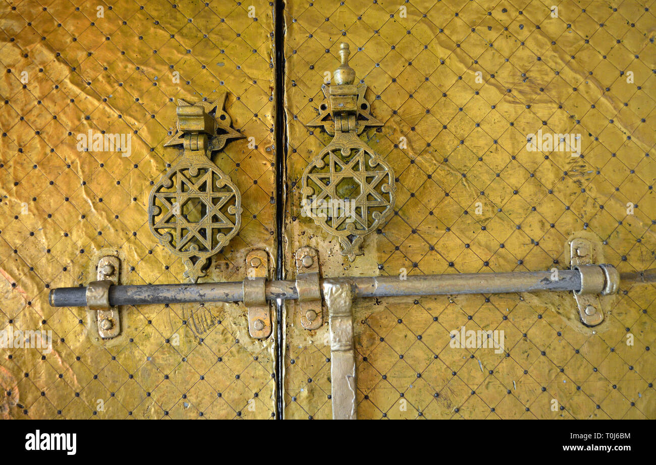 Dettaglio di un lucido dorato ottone islamica porta con una serratura e due intricate decorate maniglie di porte, visto di Fez, in Marocco. Foto Stock