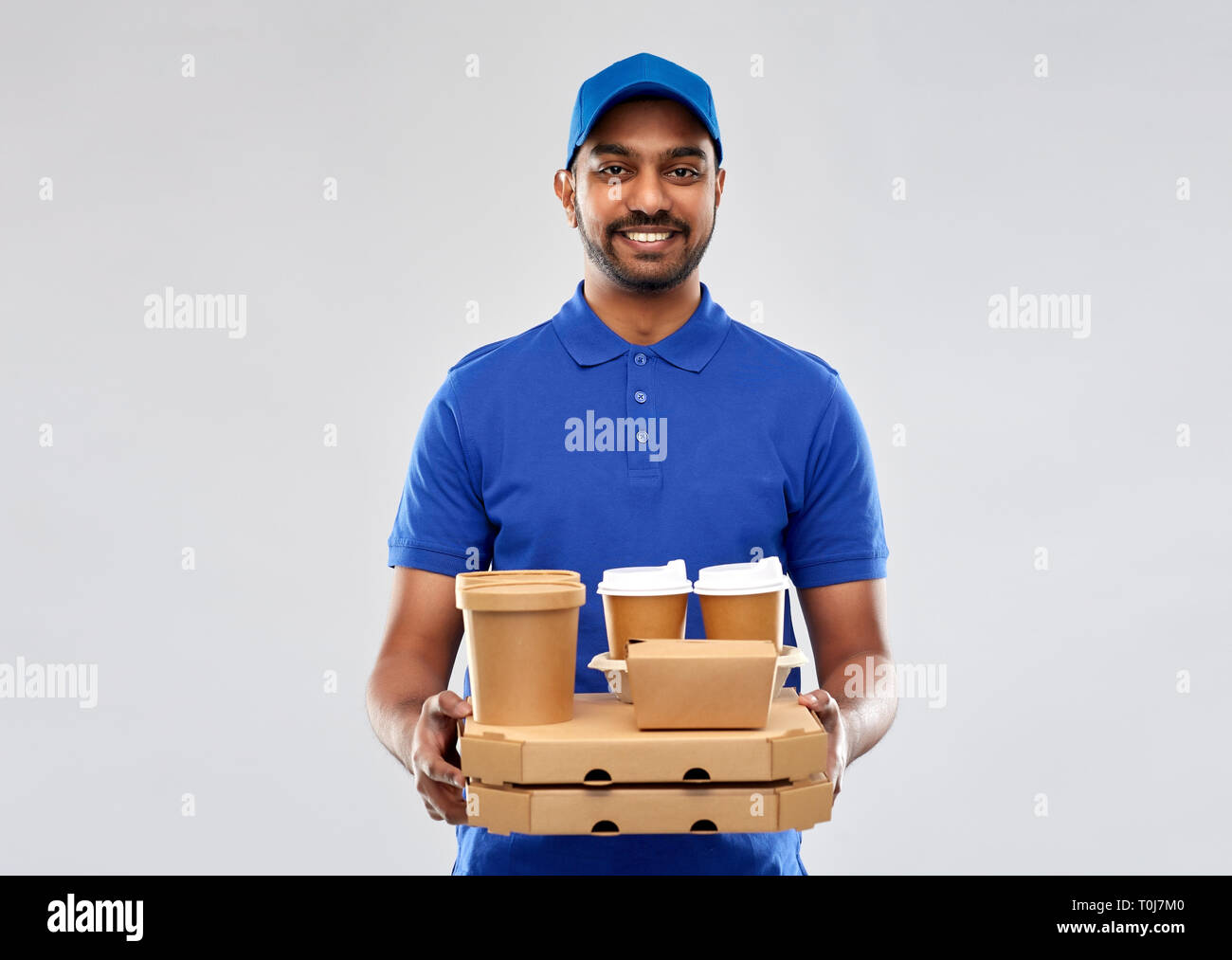 Felice di consegna indiano uomo con cibo e bevande Foto Stock