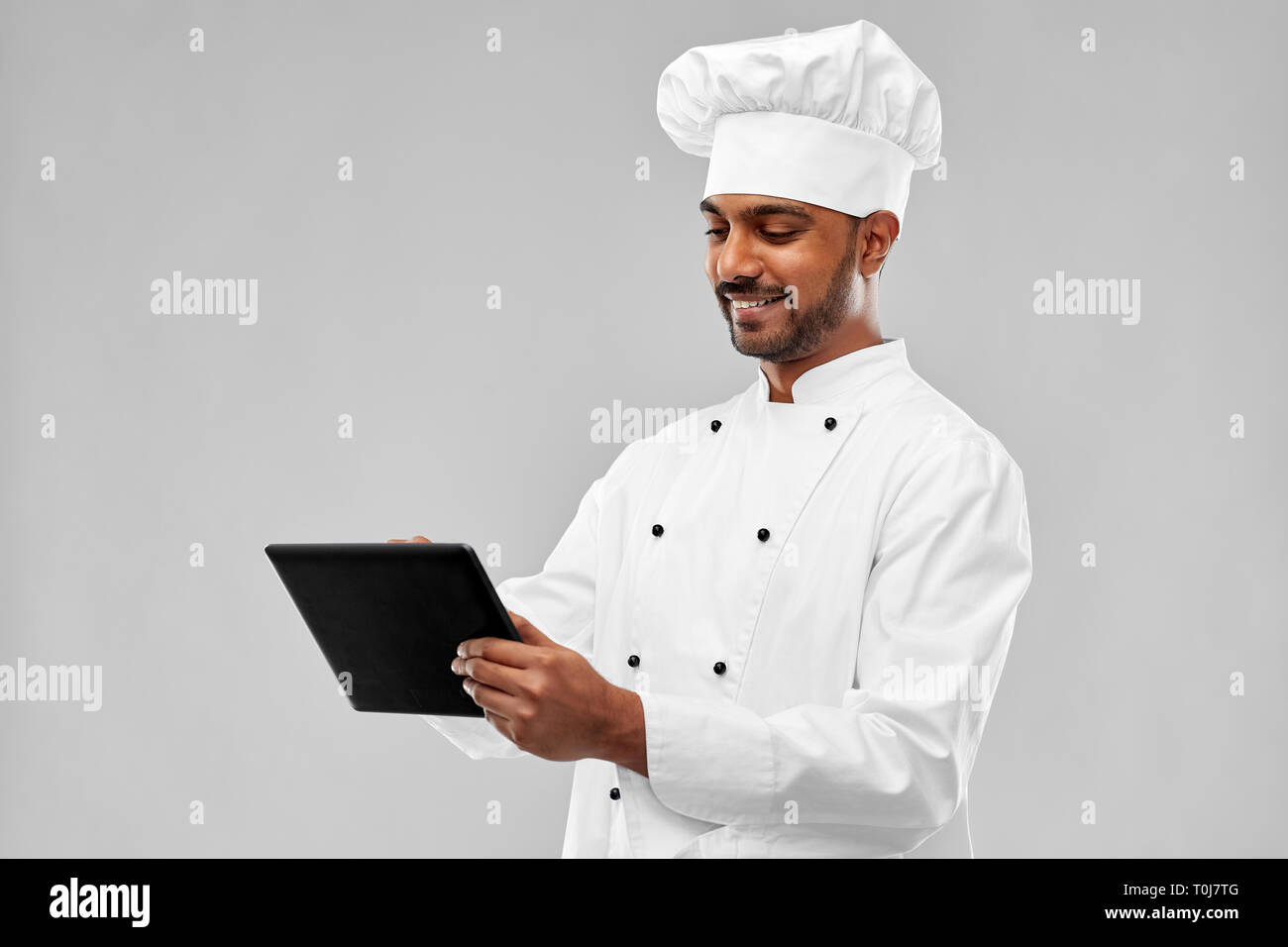 Felice maschio chef indiano con computer tablet Foto Stock
