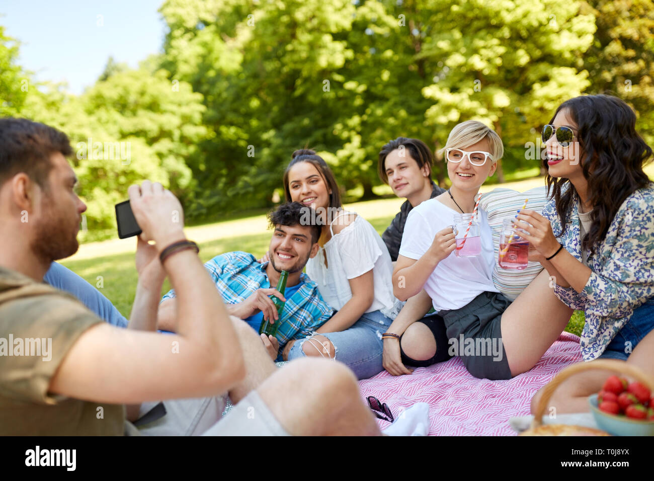 Ragazzo di scattare una foto di amici su picnic estivo Foto Stock