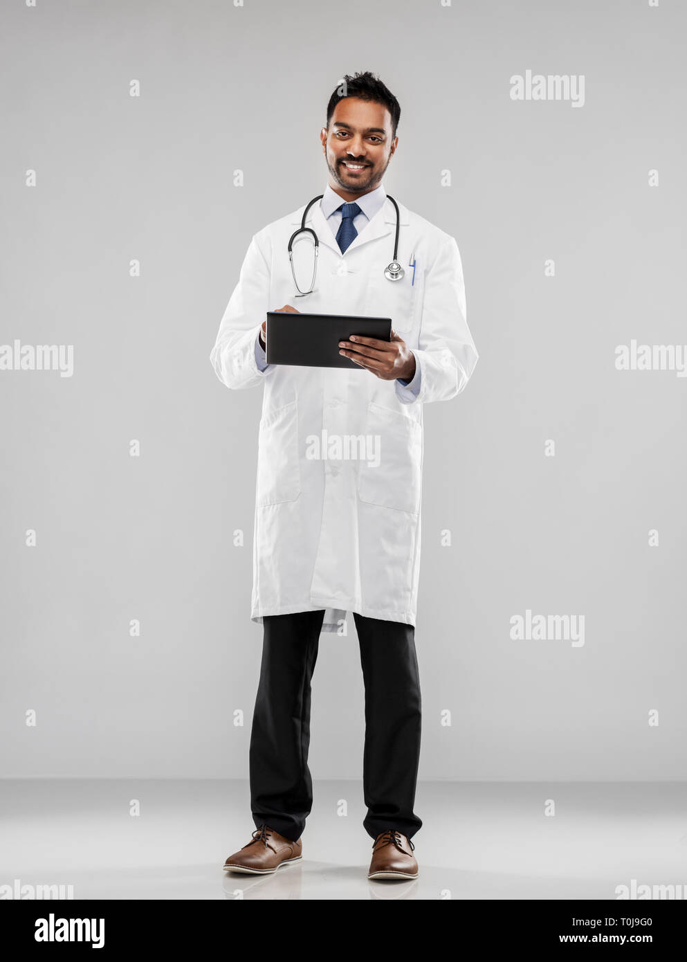 Sorridente maschio indiano medico con computer tablet Foto Stock