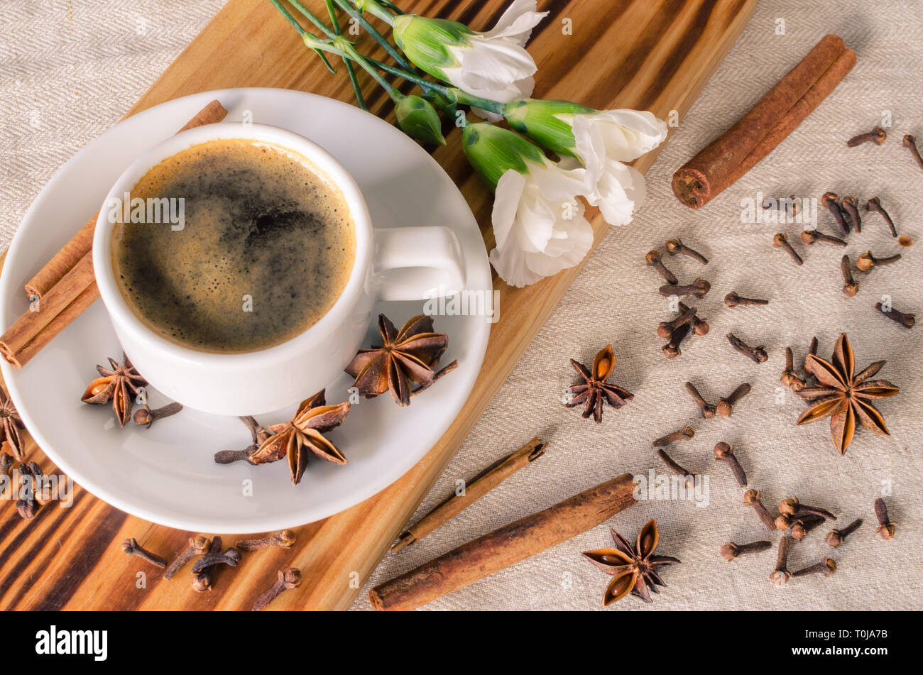 Una tazza di caffè espresso, bastoncini di cannella, anis stelle e garofani  bianchi sulla scrivania in legno e tessuto sfondo. Buongiorno! Foto stock -  Alamy
