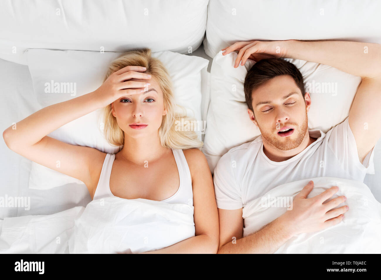 Donna infelice nel letto con il russare dorme uomo Foto Stock