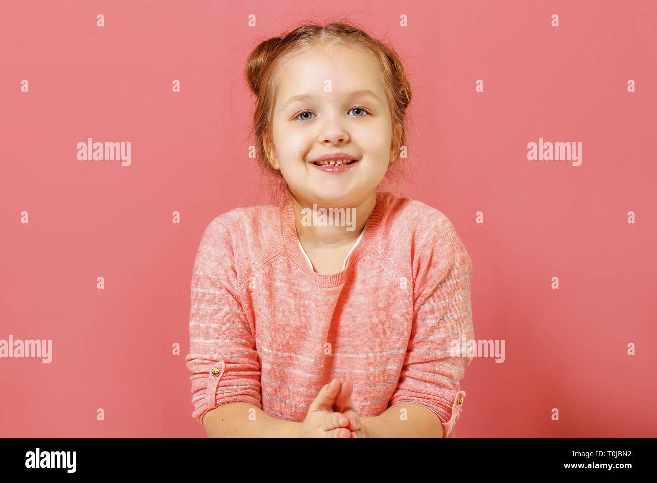 Closeup ritratto di grazioso fanciullo ragazza con ciambelle di capelli su sfondo rosa Foto Stock