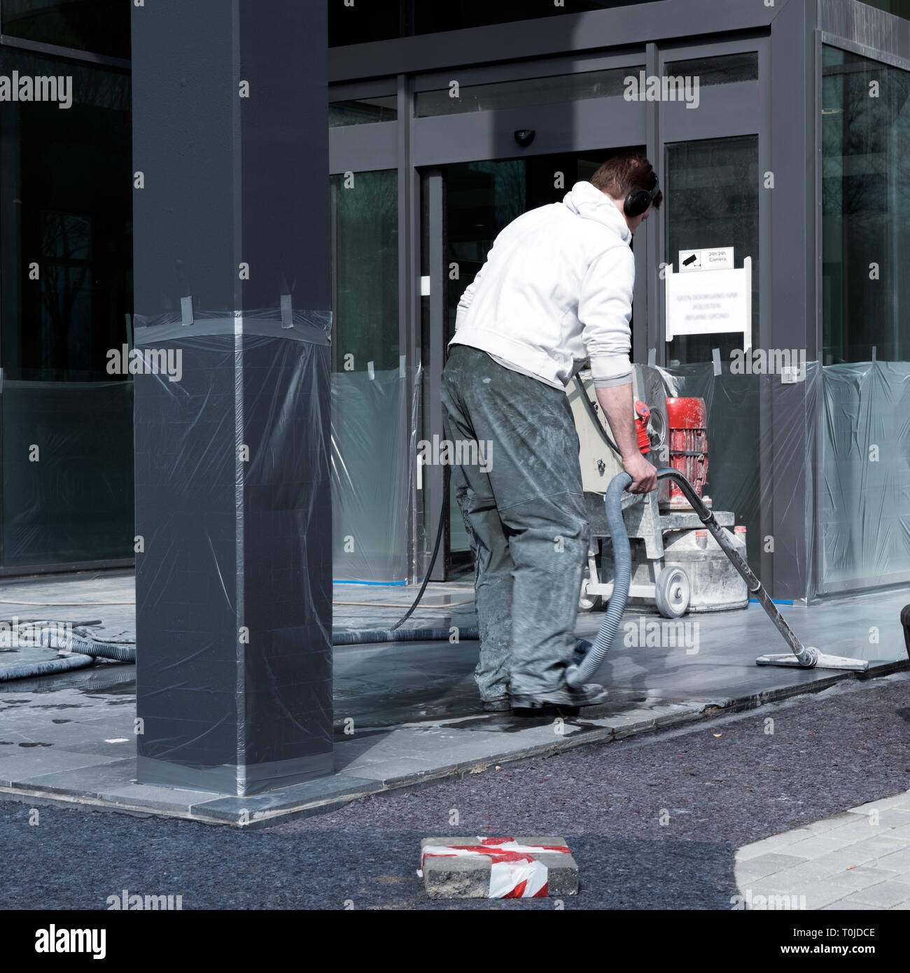 L'uomo pulisce e leviganti per pavimento in marmo di edificio per uffici con la macchina Foto Stock