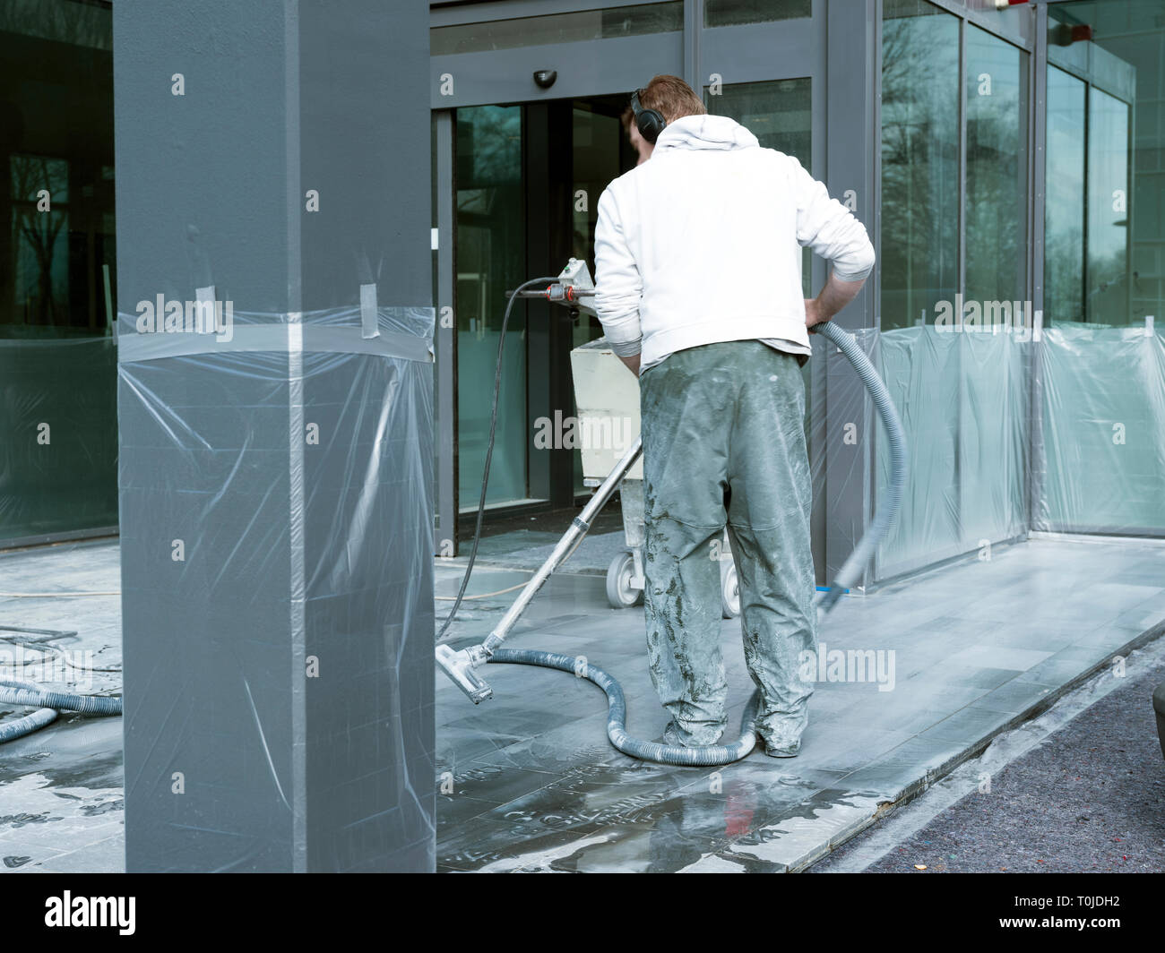 L'uomo pulisce e leviganti per pavimento in marmo di edificio per uffici con la macchina Foto Stock