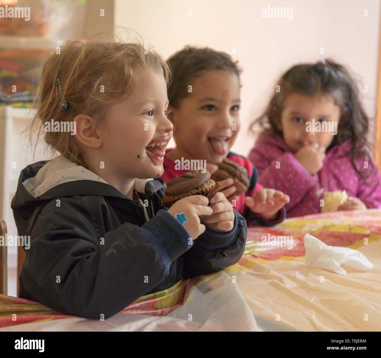 I bambini godono i tortini a una festa di compleanno a pre-scuola Foto Stock