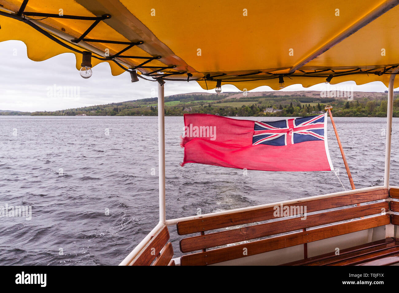 Vista posteriore da un battello da crociera sul Loch Lomond Scozia,con la Red Ensign bandiera al vento Foto Stock