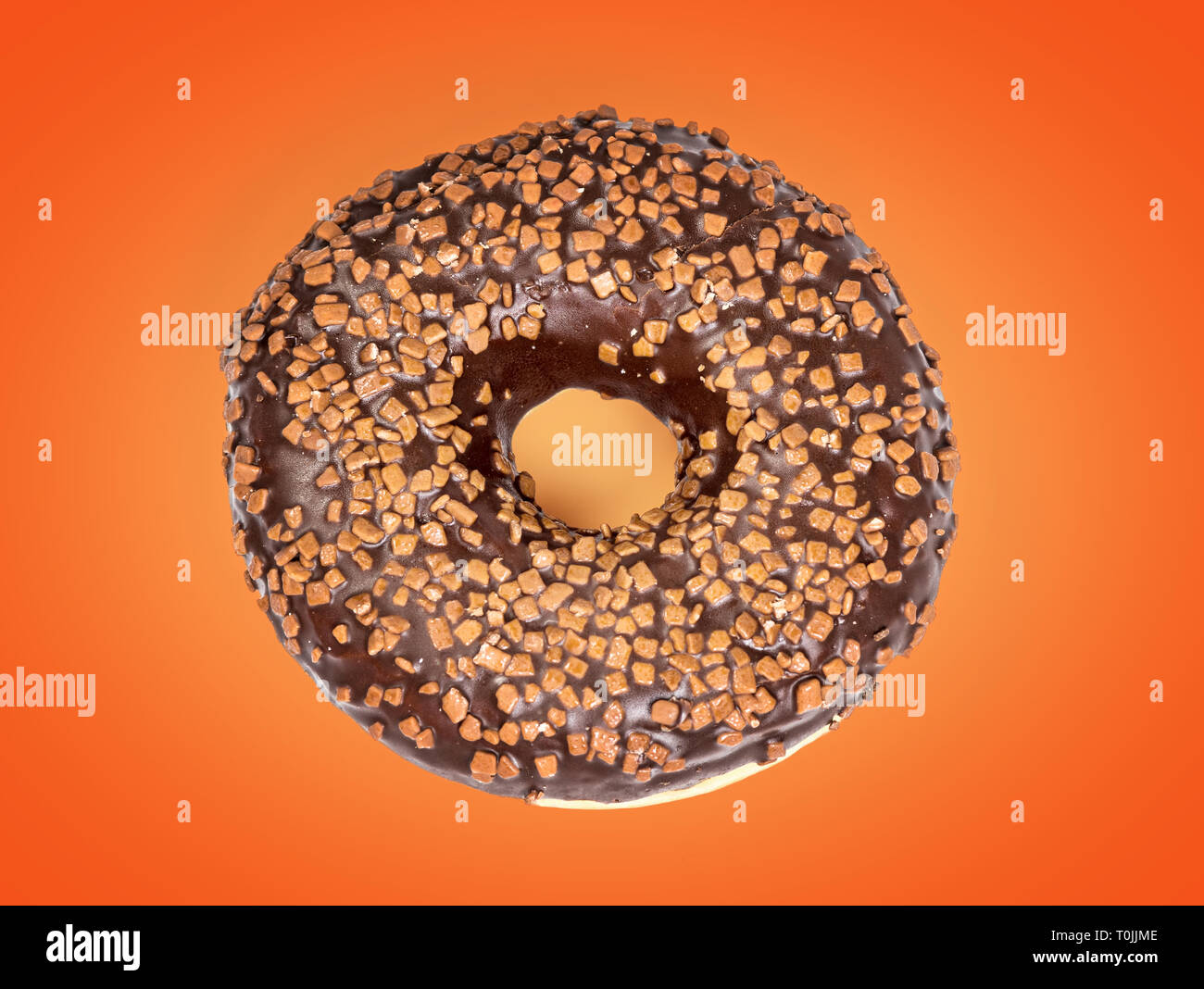 Dolce ciambella di cioccolato isolato su sfondo arancione Foto Stock
