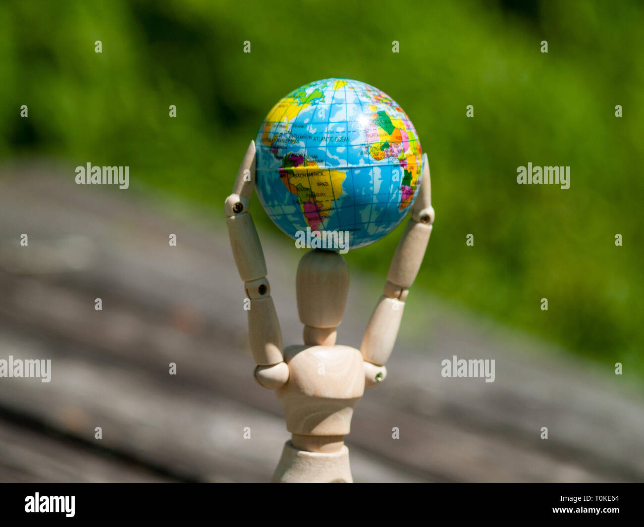 Un manichino di legno con una sfera del mondo nelle sue braccia. Concetto di ecologia, la globalizzazione Foto Stock