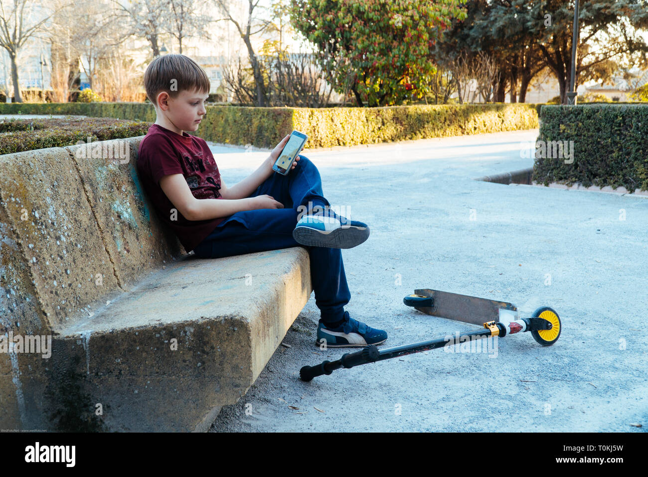 Il problema attuale dei bambini e telefoni cellulari, compresse. Un bambino nel parco giochi con un telefono cellulare. Foto Stock