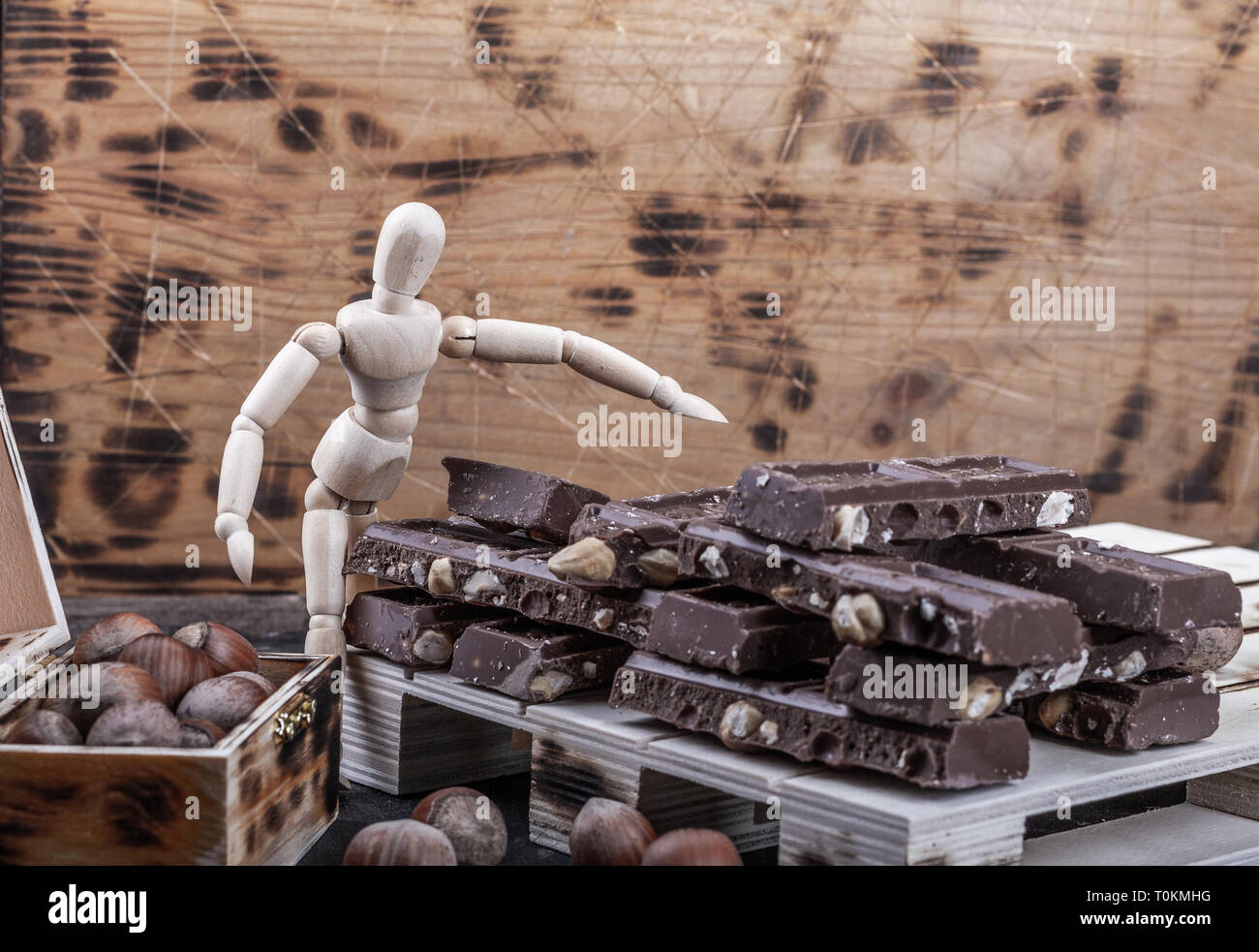 Grandi quantità di cioccolato al latte in pile su schede. Le nocciole in una cassa. Foto Stock