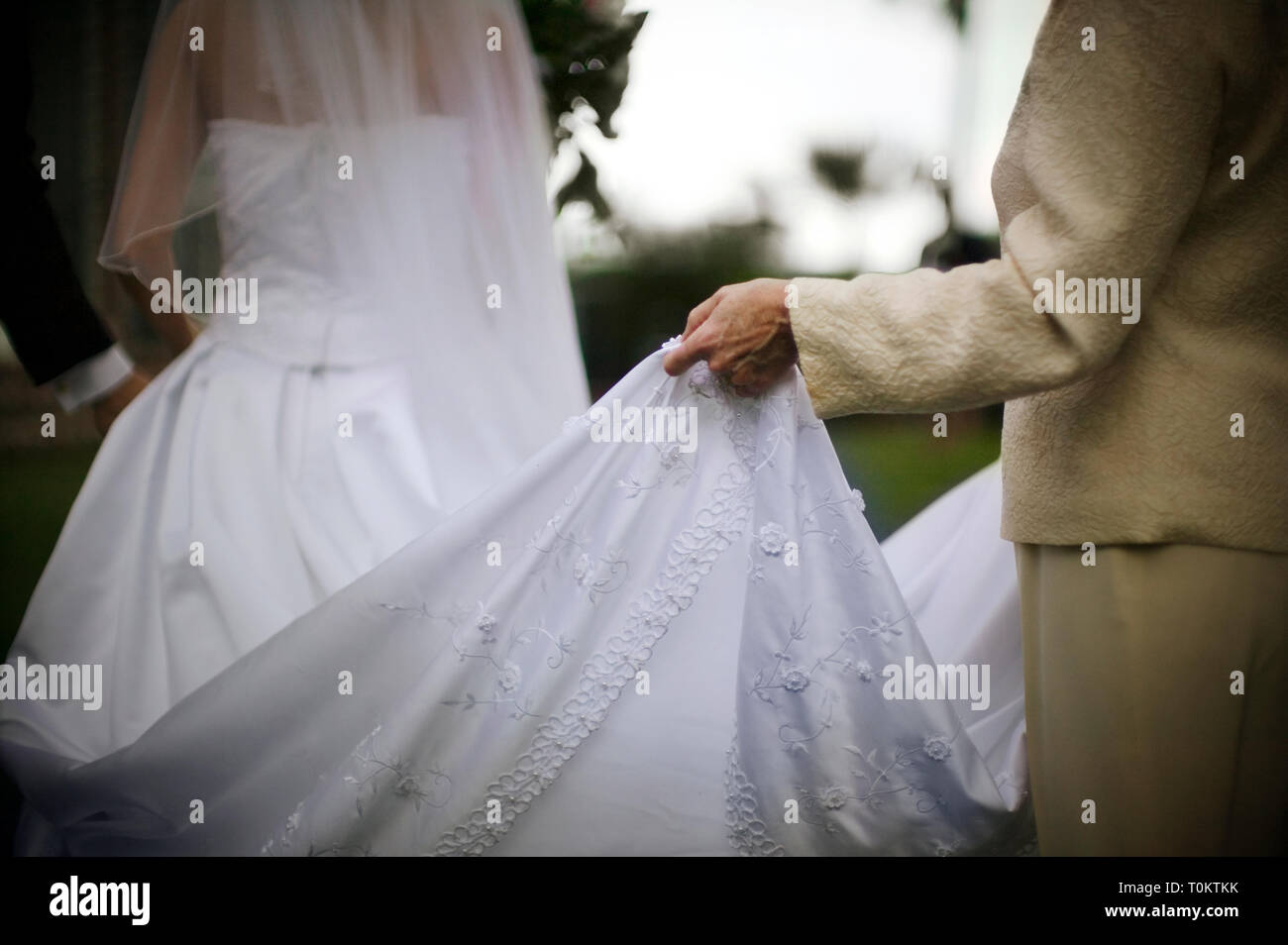 Abito da sposa treno essendo sollevata da una donna. Foto Stock