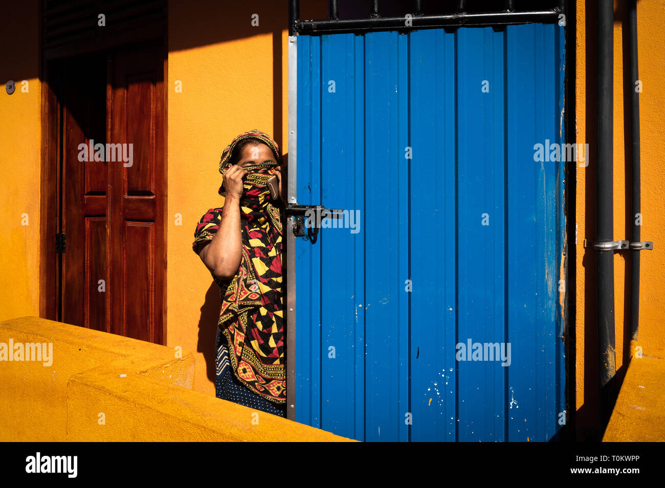 La donna nasconde il suo volto dietro una sciarpa davanti a casa sua, Colombo, Sri Lanka Foto Stock