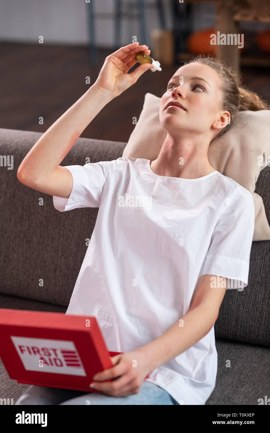 Skinny giovane donna in t-shirt bianca con il gocciolamento di gocce per gli occhi Foto Stock