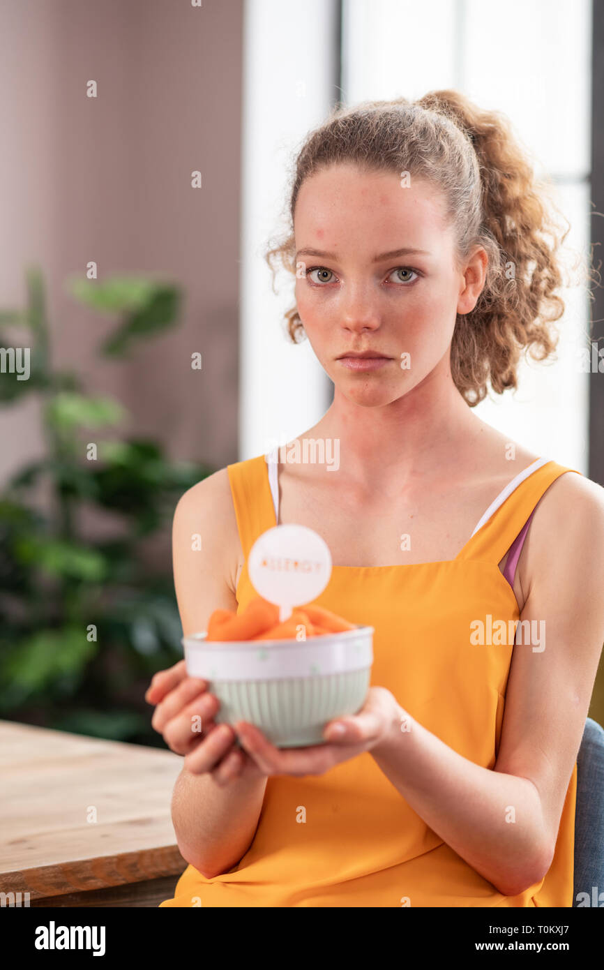 Sconvolto bella donna con gli occhi la luce avente allergia su frutti nel recipiente Foto Stock