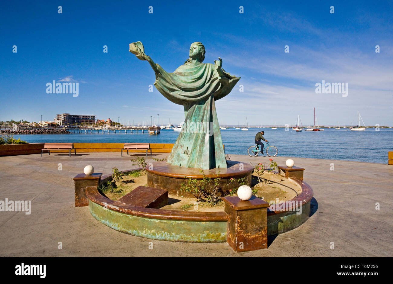 Un uomo messicano in sella alla sua moto nei pressi di una delle numerose sculture che punteggiano il Malecon e la zona fronte mare sulla baia di La Paz a Baja, Messico. Foto Stock