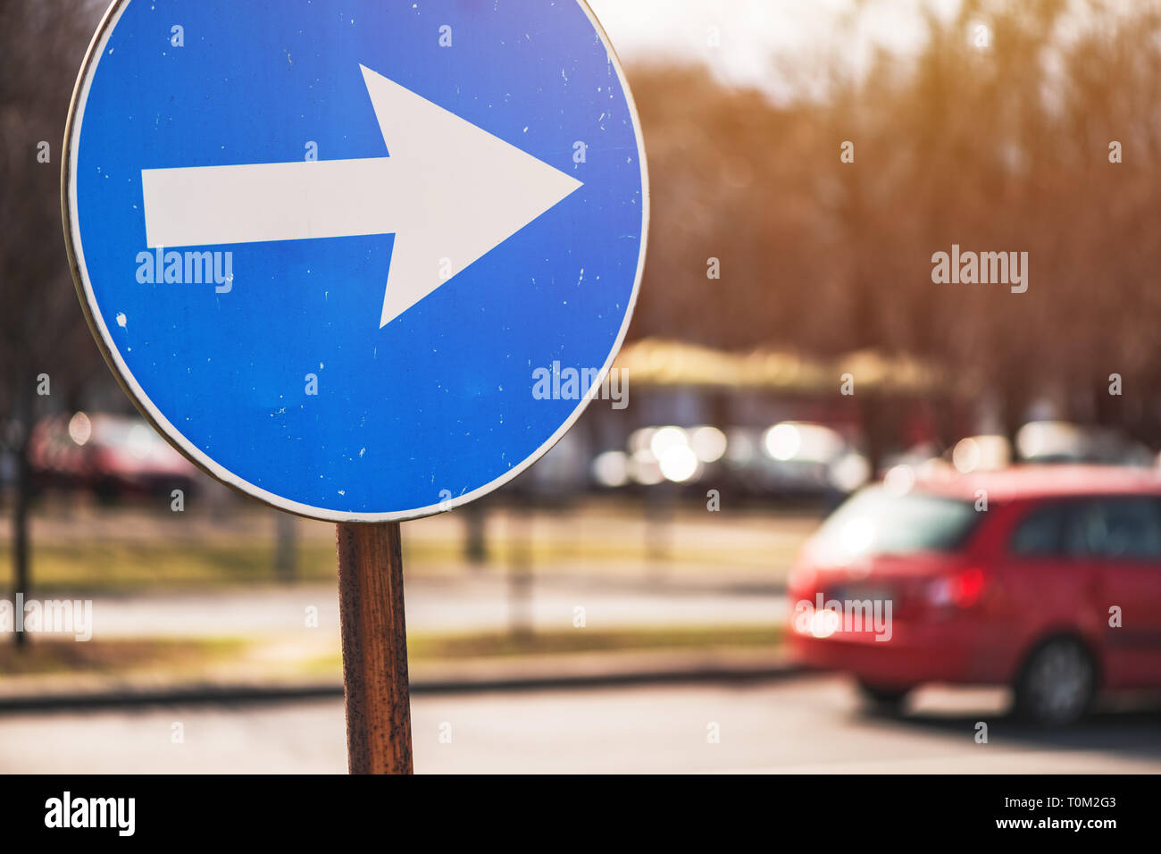 Procedere in direzione di freccia segno del traffico su strada con il veicolo defocussed in background Foto Stock