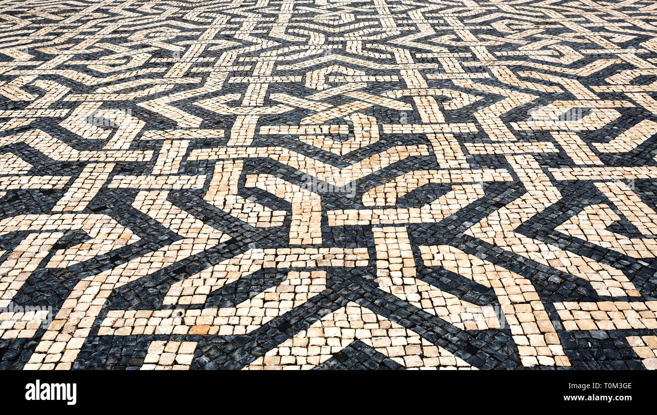 Tipica portoghese cobblestone pavement creazione di nero e di bianco utilizzando modelli di basalto e ciottoli di calcare, a Lisbona, Portogallo Foto Stock