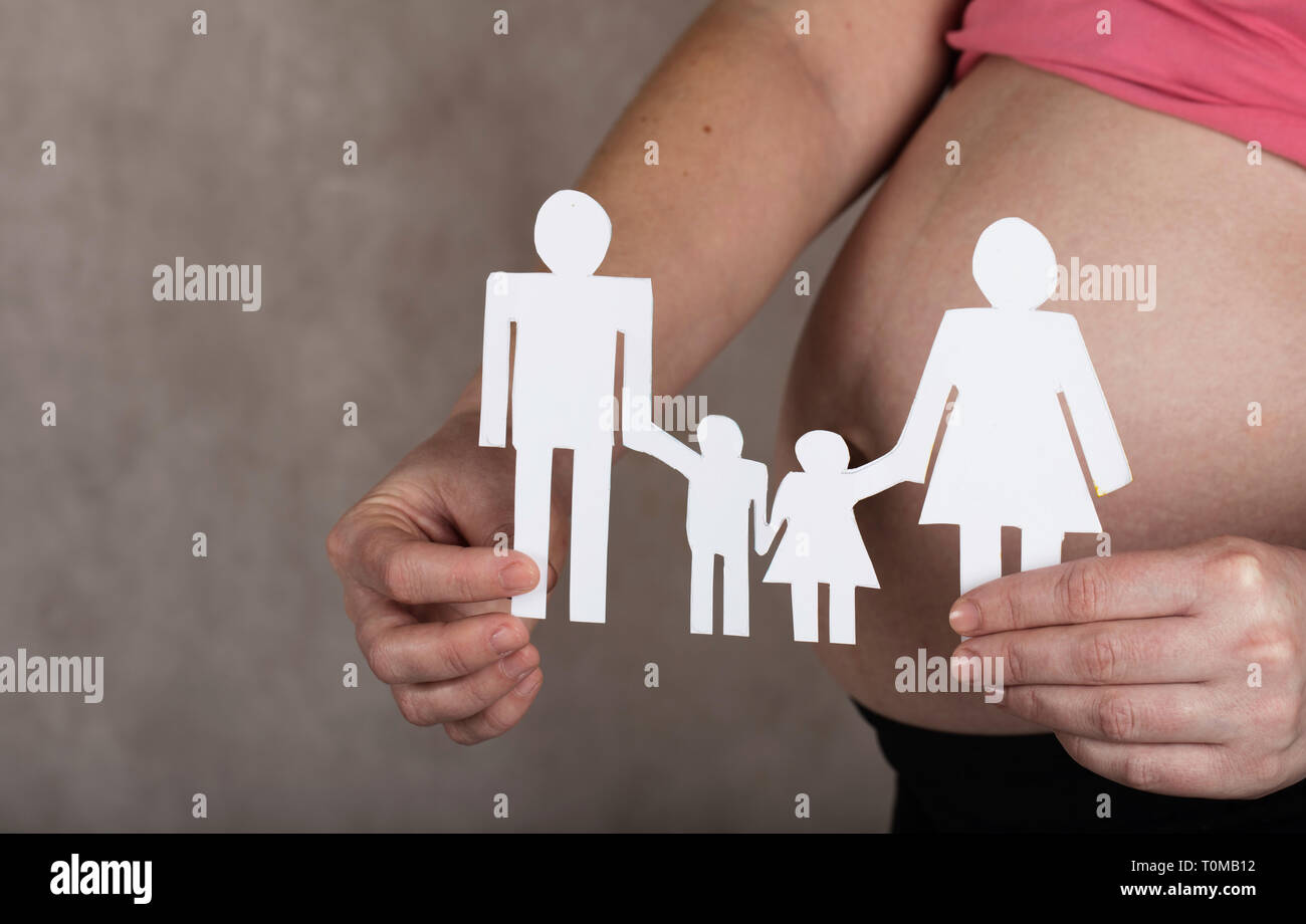 Gravidanza giovani tra i 30 e i 35 anni donna mantiene ritagli di una famiglia. Primo piano Foto Stock