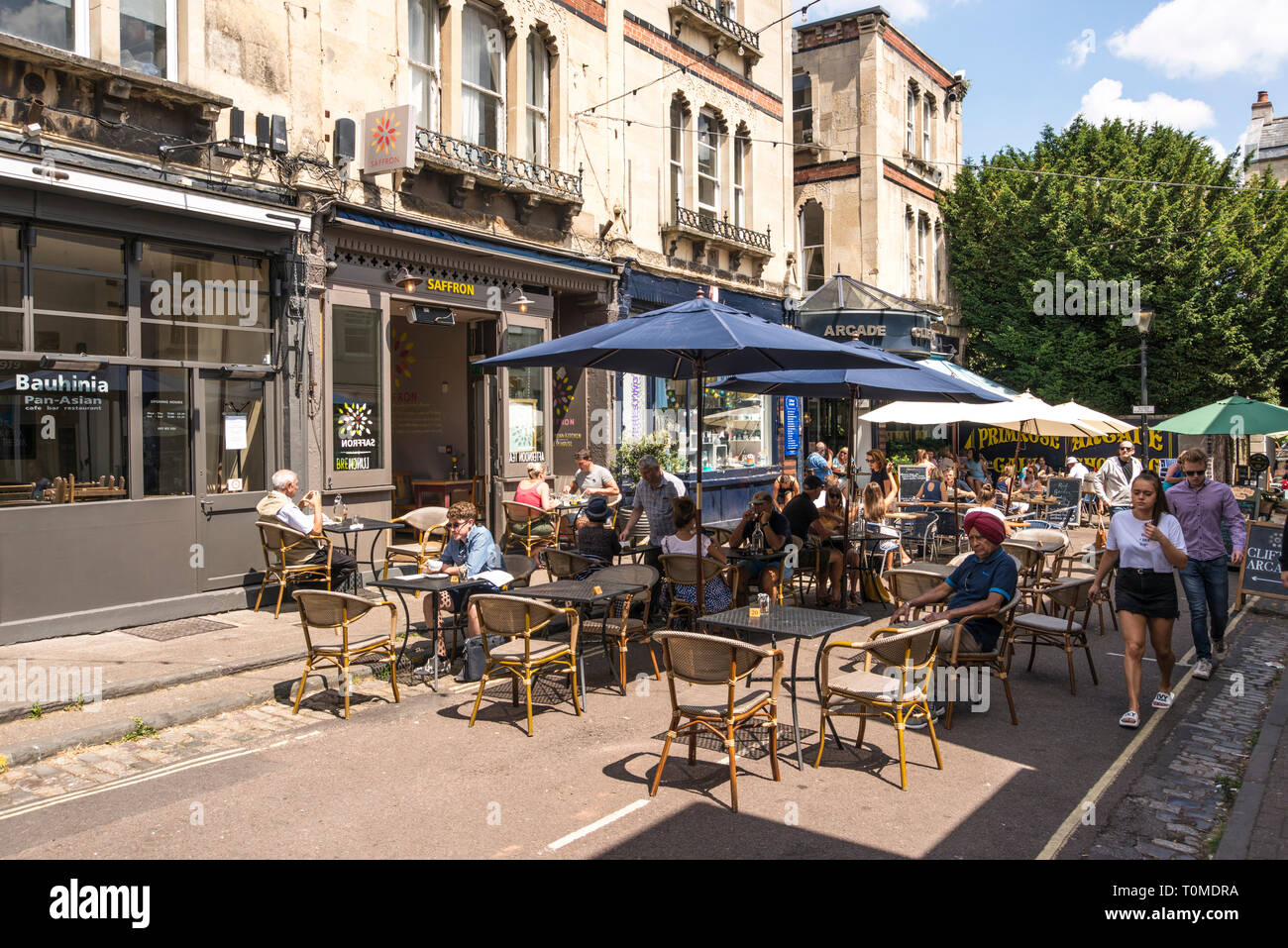 La gente seduta al di fuori di godersi le giornate di sole e caffè, Boyces Ave, Bristol, Regno Unito Foto Stock