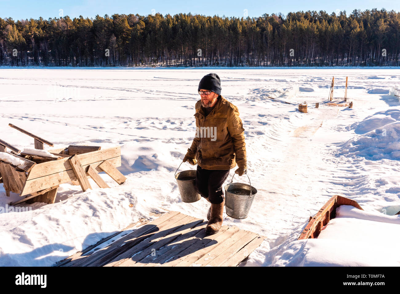 L uomo recupera acqua con due benne da congelati Lago Baikal, Siberia, Russia Foto Stock