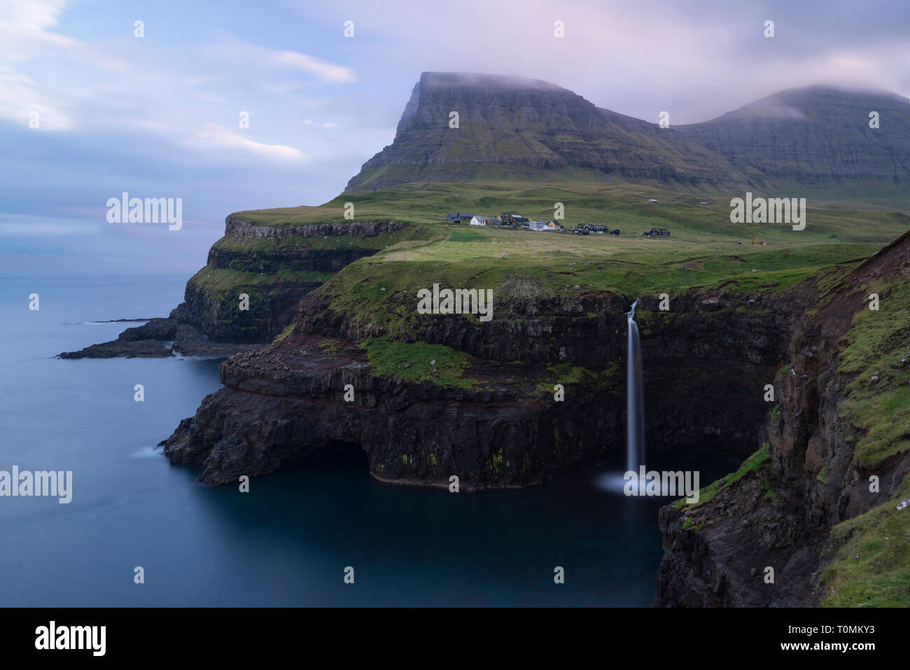 Alba sulla costa scoscesa con cascata in Gásadalur, Vágar, Isole Faerøer, Danimarca Foto Stock