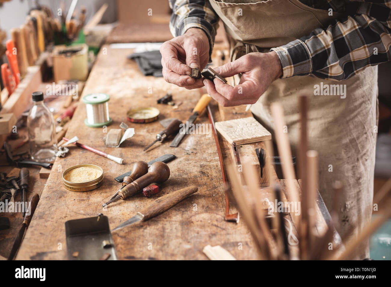 Artigiano accanto a un banco di lavoro rustico con strumenti Foto Stock