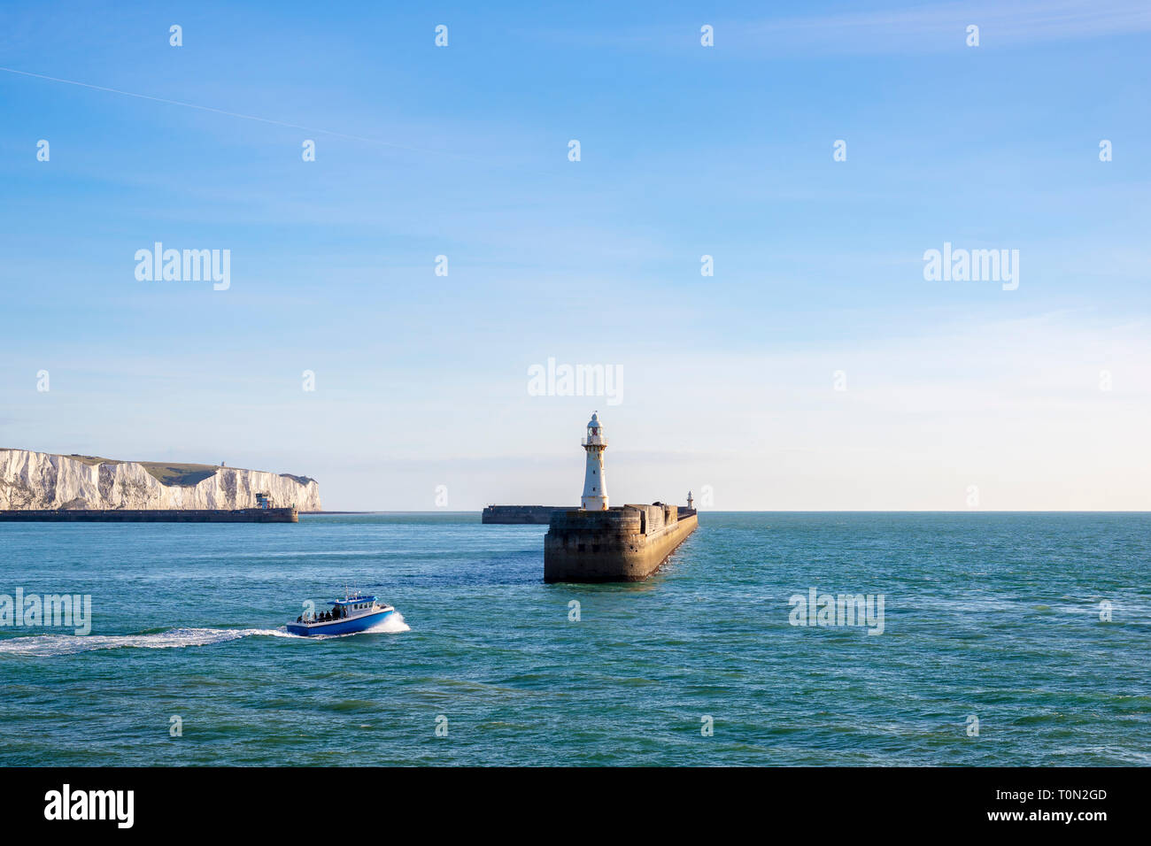 Una barca da pesca di lasciare il porto di Dover; con la mitica Bianche Scogliere in background. Foto Stock