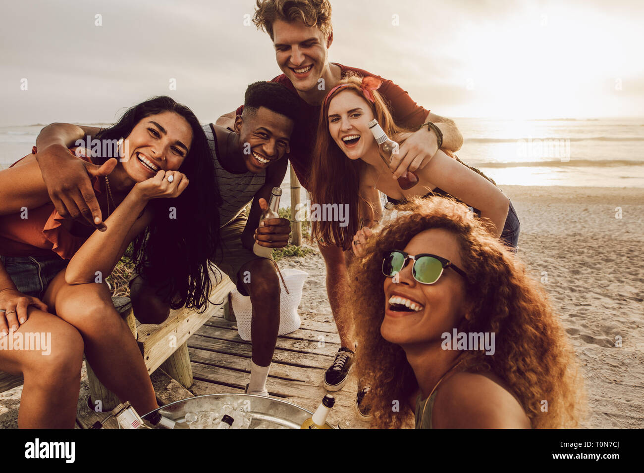Giovane donna parlando selfie con diversi gruppi di amici in spiaggia. Multirazziale giovani uomini e giovani donne che posano per una selfie. Foto Stock