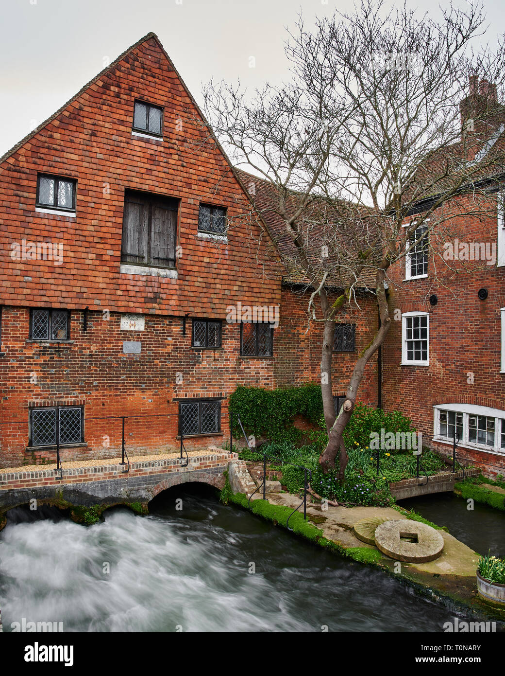 Il veloce che scorre il fiume Itchen sotto la storica città di Winchester Watermill. Una lunga esposizione fotografia per catturare il potente flusso d'acqua. Foto Stock