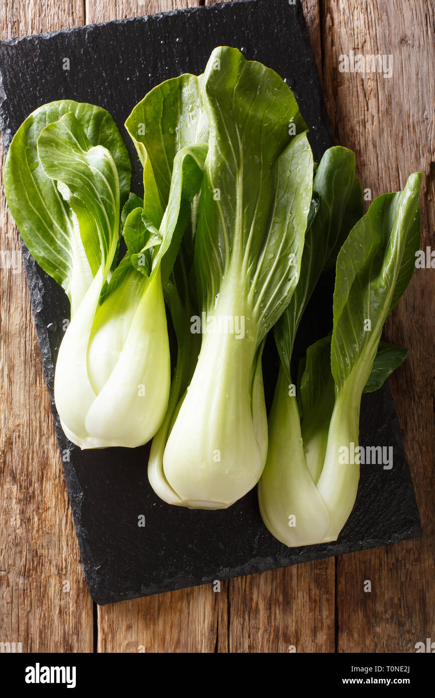 Cibo sano baby bok choy cinesi Cavoli a foglia su una scheda di ardesia sul tavolo. Verticale in alto vista da sopra Foto Stock