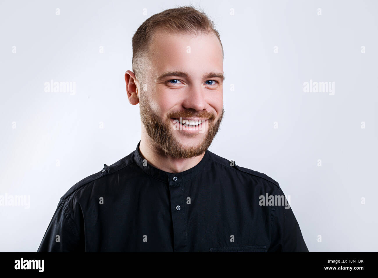 Ritratto di un bel giovane uomo sorridente su sfondo grigio Foto Stock