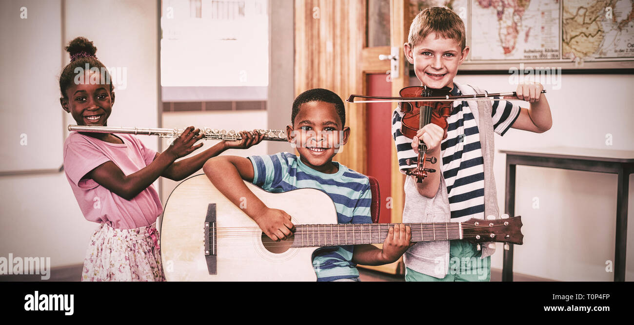 Ritratto di bambini che giocano gli strumenti musicali in aula Foto Stock