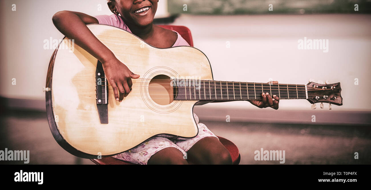 Ritratto di sorridere schoolgirl suonando la chitarra in aula Foto Stock