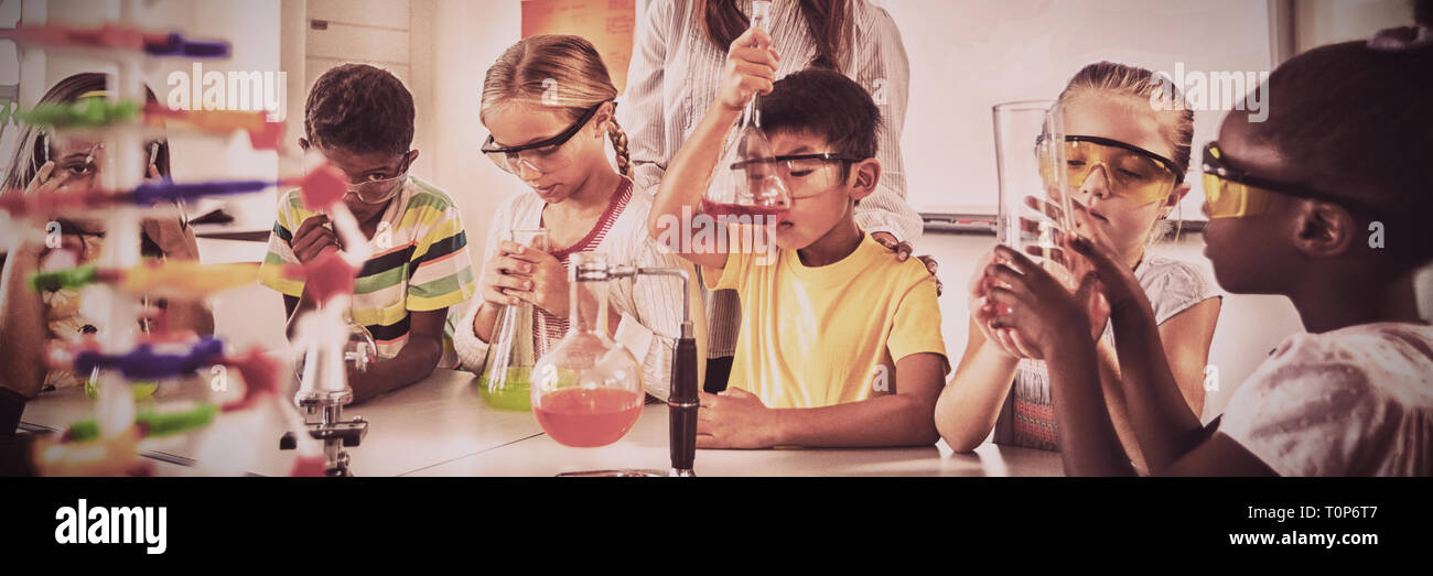 Un insegnante in posa con gli alunni fare scienza progetto Foto Stock