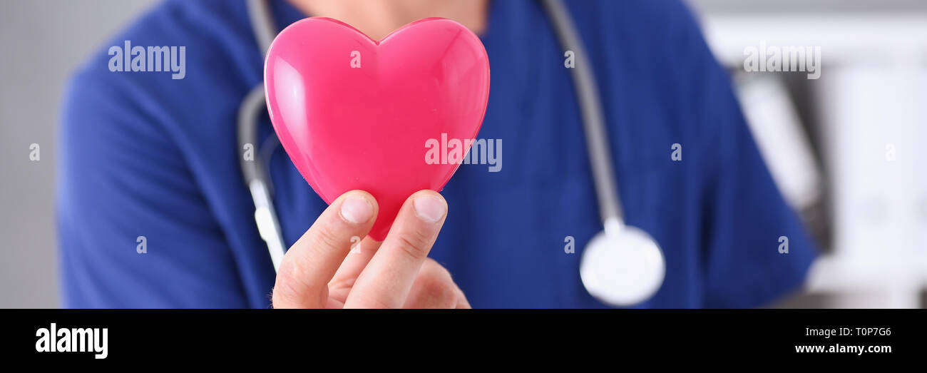 Medico maschio tenere in armi cuore rosso Foto Stock