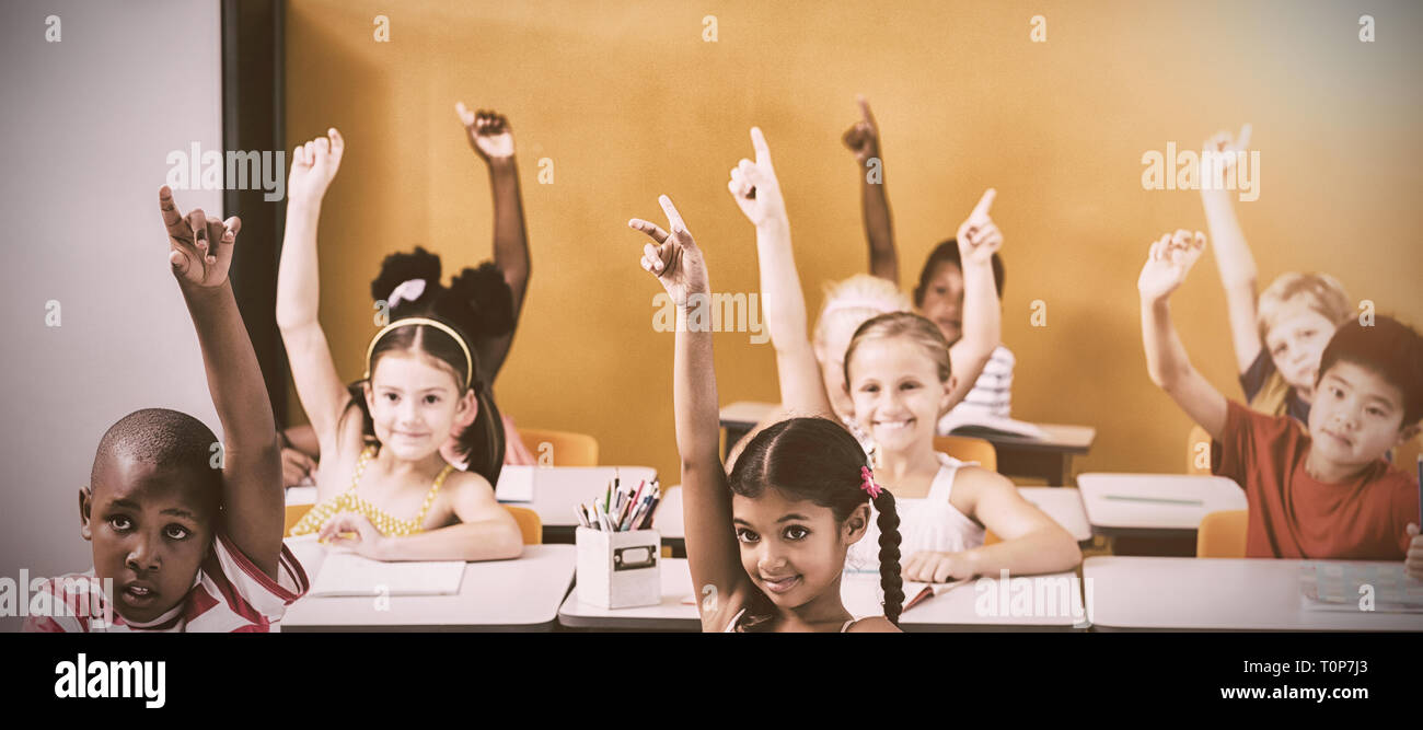 Gli studenti alzando le mani in aula Foto Stock