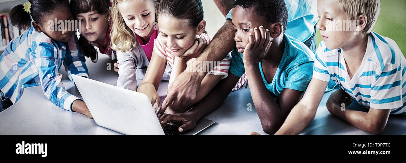 Insegnanti e bambini che utilizzano computer portatile in biblioteca Foto Stock