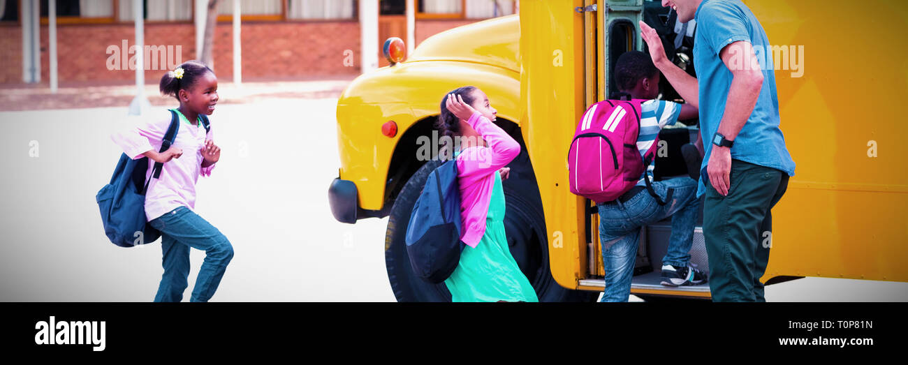 Docente dando alta cinque per i bambini mentre entrando in autobus Foto Stock