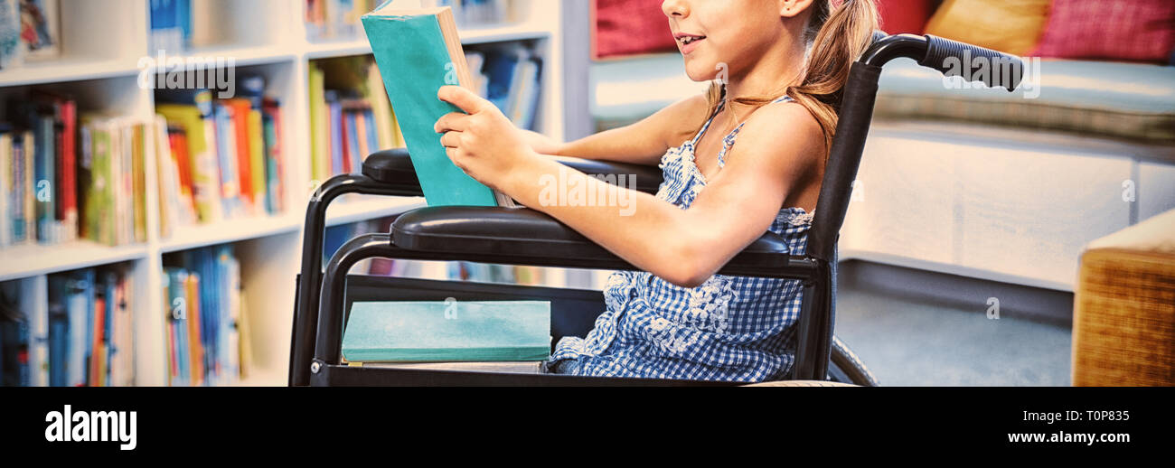 Ragazza disabili la lettura di libro in biblioteca Foto Stock