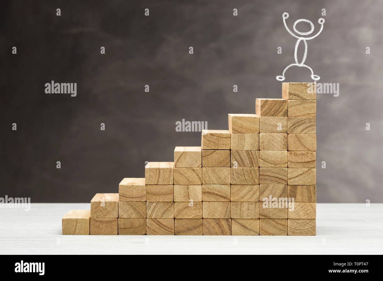 Concetto di crescita. Grafico con gradini in legno su uno sfondo grigio, con forma umana sulla parte superiore. Foto Stock