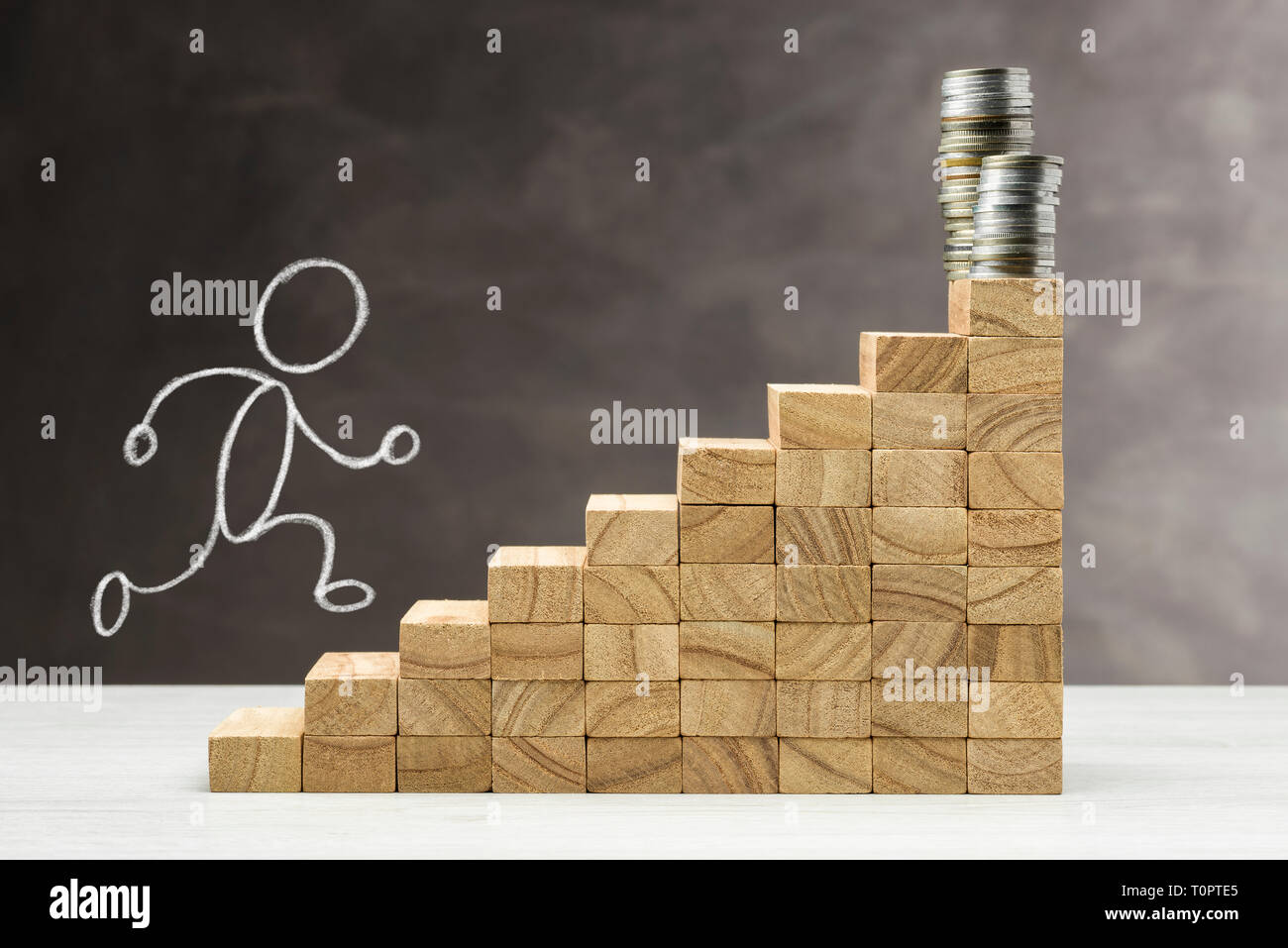 Concetto di crescita. Grafico con gradini in legno su uno sfondo grigio con la pila di monete sulla parte superiore e la forma umana che sorge. Foto Stock