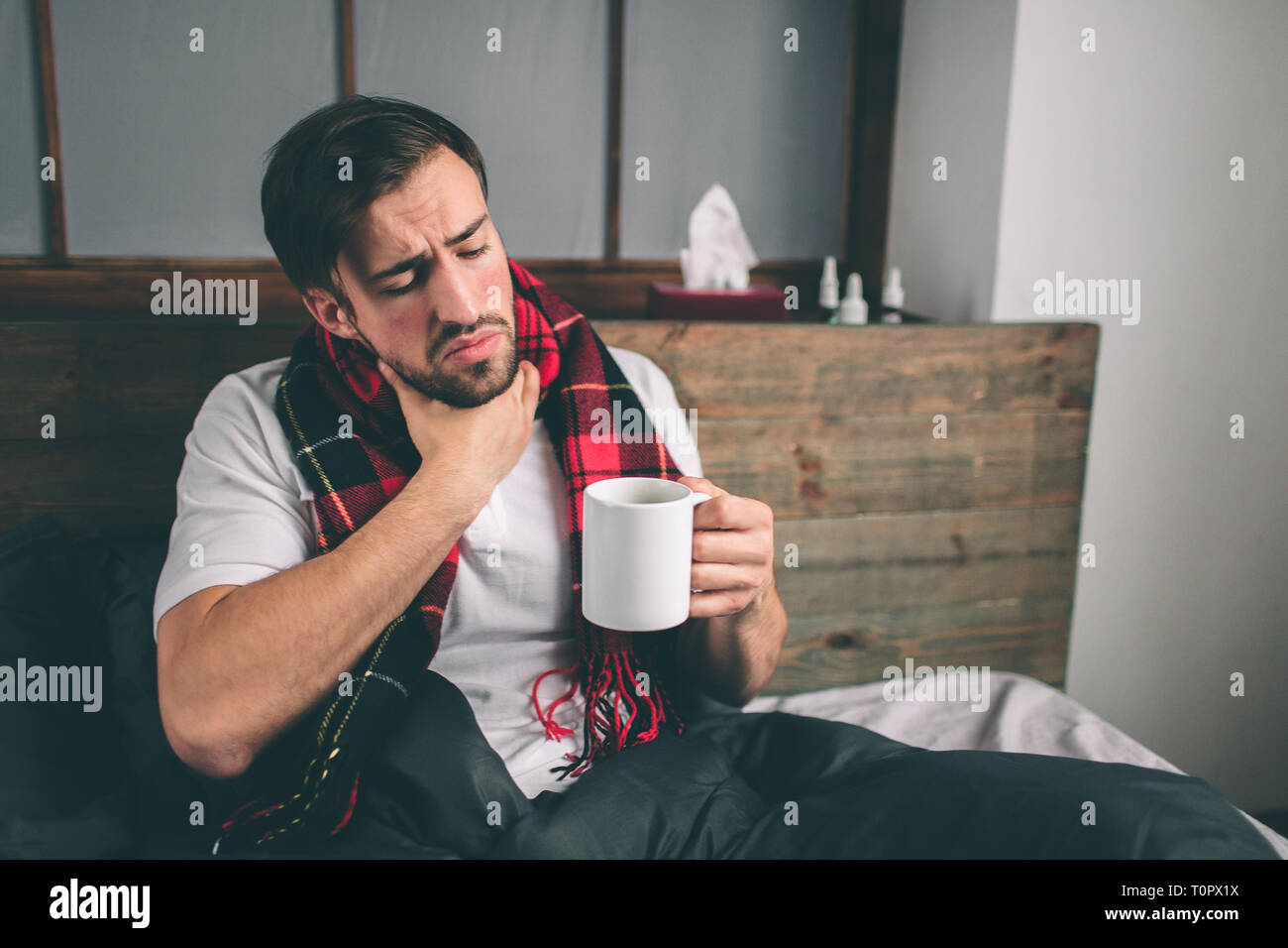 Immagine da un giovane con fazzoletto. Ragazzo malato si trova nel letto e ha naso che cola. uomo fa una cura per il raffreddore comune modello maschio ha una alta temper Foto Stock